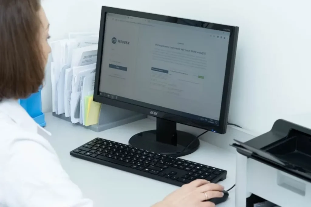 Profissional da saúde consultando sistema com código TUSS creatinina em tela de computador.