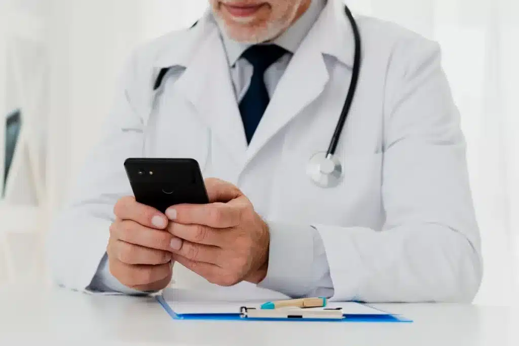 Médico com jaleco usando celular, contexto do app Amplimed