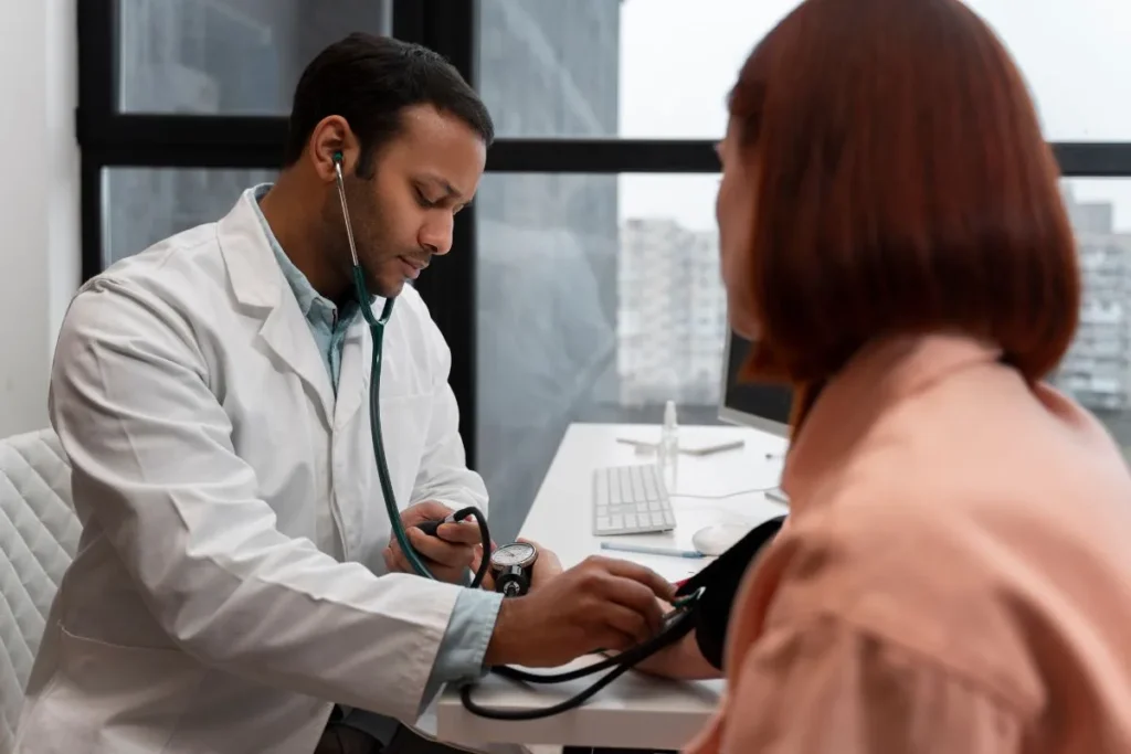 Médico aferindo a pressão de paciente durante consulta presencial, etapa importante para registrar a história patológica pregressa.