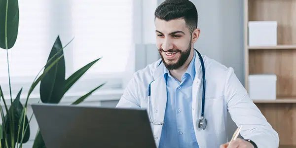 Profissional da saúde de frente para computador, acessando prontuário eletrônico.