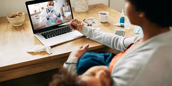 Mãe mede temperatura de criança em teleconsulta com pediatra