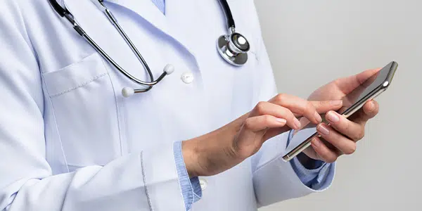 Profissional da saúde acessando sistema com armazenamento em nuvem pelo celular.