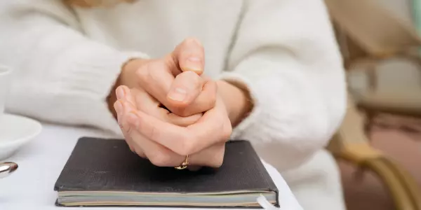 Detalhe de mãos segurando uma na outra em uma consulta de anamnese psicológica