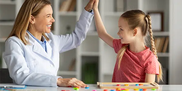 Médica brincando com menina de cerca de 10 anos